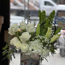 White roses and lilies arranged in a mirrored vase