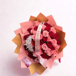 Bouquet of pink and red roses wrapped in pink paper with a ribbon