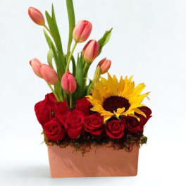 Pink tulips and red roses with a sunflower in a square vase