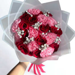 Bouquet of red roses and pink carnations wrapped in translucent paper