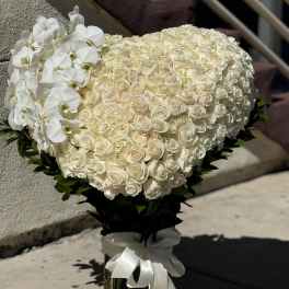 Heart-shaped bouquet of white roses with white orchids and a ribbon wrap
