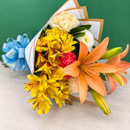 Bouquet of yellow and orange flowers wrapped in white paper with a blue ribbon