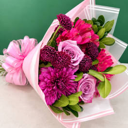 Pink and purple bouquet wrapped in clear and pink paper with a ribbon bow