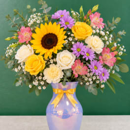 Mixed bouquet in a lavender vase with a yellow ribbon