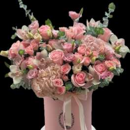 Pink rose and orchid arrangement in a pink hat box with ribbon