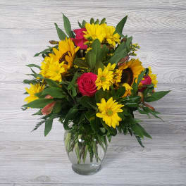 Bouquet of yellow daisies and pink roses in a clear glass vase