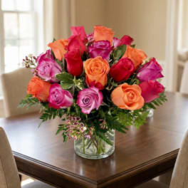 Bouquet of pink, red, and orange roses in a clear glass vase