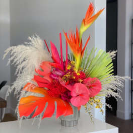 Bright tropical bouquet in a striped vase with pink and orange blooms