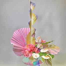 Pink roses with white anthuriums and metallic tropical leaves in a vase