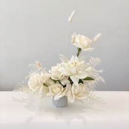 White rose arrangement in a small ribbed vase with airy dried accents