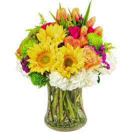 Bright mixed bouquet in a clear glass vase with sunflowers, roses, tulips, and hydrangeas