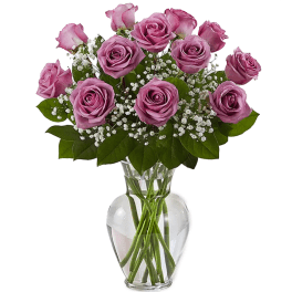 Arrangement of lavender roses with white filler flowers in a clear glass vase