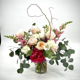 Mixed bouquet of roses, peonies, and snapdragons in a glass vase