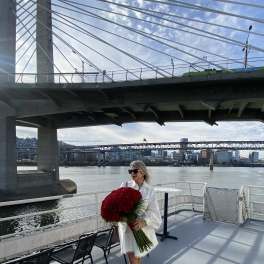 Woman holding a large bouquet of red flowers on a boat deck