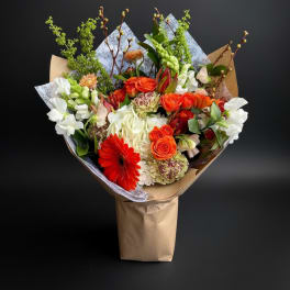 Bouquet of orange, white, and red flowers wrapped in brown paper