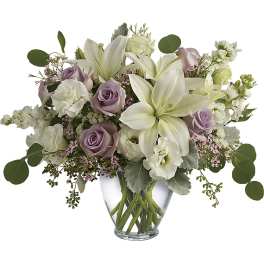 Bouquet of white lilies and lavender roses in a clear glass vase