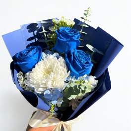 Bouquet of blue roses and white flowers wrapped in dark blue paper
