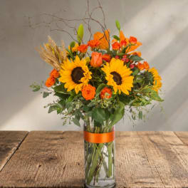Sunflower and orange rose bouquet in a clear glass vase