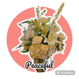 Cream-colored floral bouquet with roses, lilies, and hydrangea in a glass vase