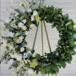 Floral wreath with white roses and greenery on a stand
