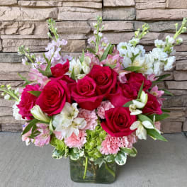Bouquet of red roses, pink carnations, and white alstroemeria in a glass vase