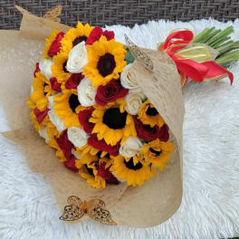 Bouquet of sunflowers and red and white roses wrapped in tan paper