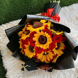 Bouquet of red roses and yellow sunflowers wrapped in black paper