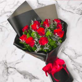 Bouquet of red roses wrapped in black paper with a red ribbon