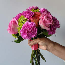 Handheld bouquet of pink roses and carnations with green accents