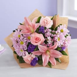 Pink lilies, roses, and daisies in kraft paper wrapping