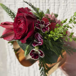 Red rose and pink blooms wrist corsage on a gold metal cuff bracelet