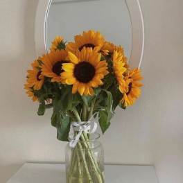 Bouquet of sunflowers in a clear glass vase with a white ribbon