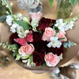 Bouquet of pink and deep red roses with white flowers wrapped in brown paper
