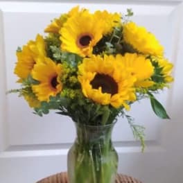 Yellow sunflowers arranged in a clear glass vase