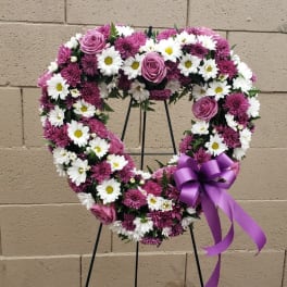 Heart-shaped floral wreath with pink roses, white daisies, and a purple ribbon