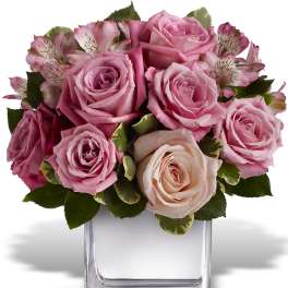 Pink roses and alstroemeria arranged in a clear square vase