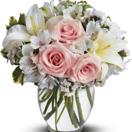 Pink roses and white lilies arranged in a clear glass vase