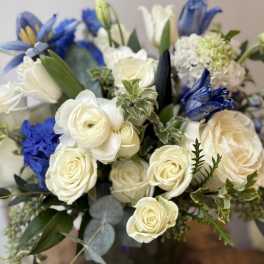 Bouquet of white roses and blue flowers with greenery