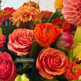 Colorful bouquet of roses, dahlias, and zinnias in a glass vase