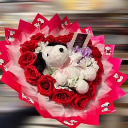 Bouquet of red roses with a Snoopy plush toy and pink wrapping
