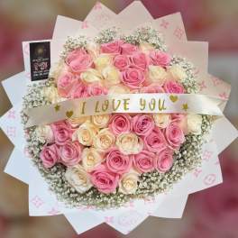 Bouquet of pink and cream roses with a ribbon reading I LOVE YOU
