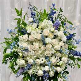 Large standing floral spray with white roses and blue flowers on an easel