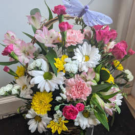Mixed flower basket with daisies, carnations, roses, and a butterfly decoration