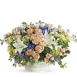 Mixed bouquet of roses and lilies in a white container