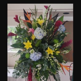 Large tropical standing floral arrangement with yellow lilies and blue hydrangeas