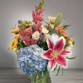 Mixed bouquet in a glass vase with blue hydrangea and pink lily