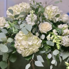 White hydrangeas and roses arranged with eucalyptus greenery