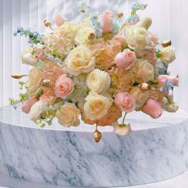 Pastel bouquet of roses and hydrangeas on a marble pedestal