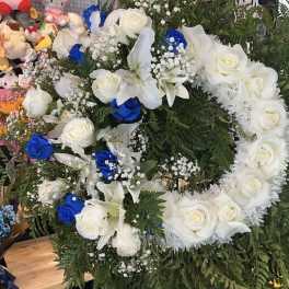 Large floral wreath of white roses, lilies, and blue roses