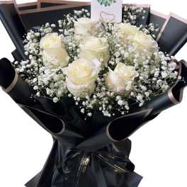Bouquet of white roses and baby's breath wrapped in black paper